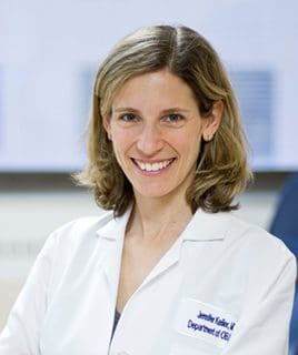 Headshot of a smiling woman in a white coat.