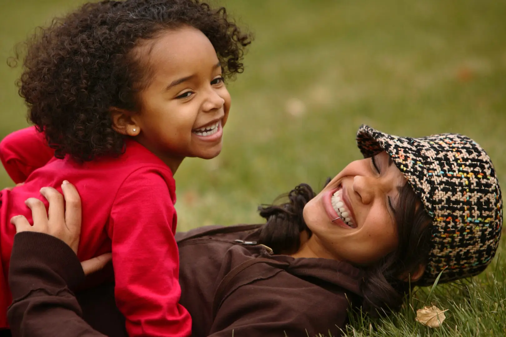 Laughing mother and daughter in grass.