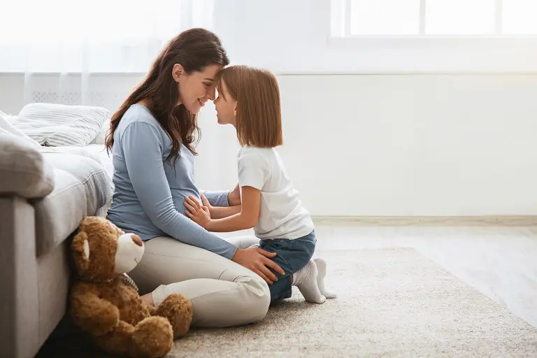 Pregnant woman and daughter cuddling.