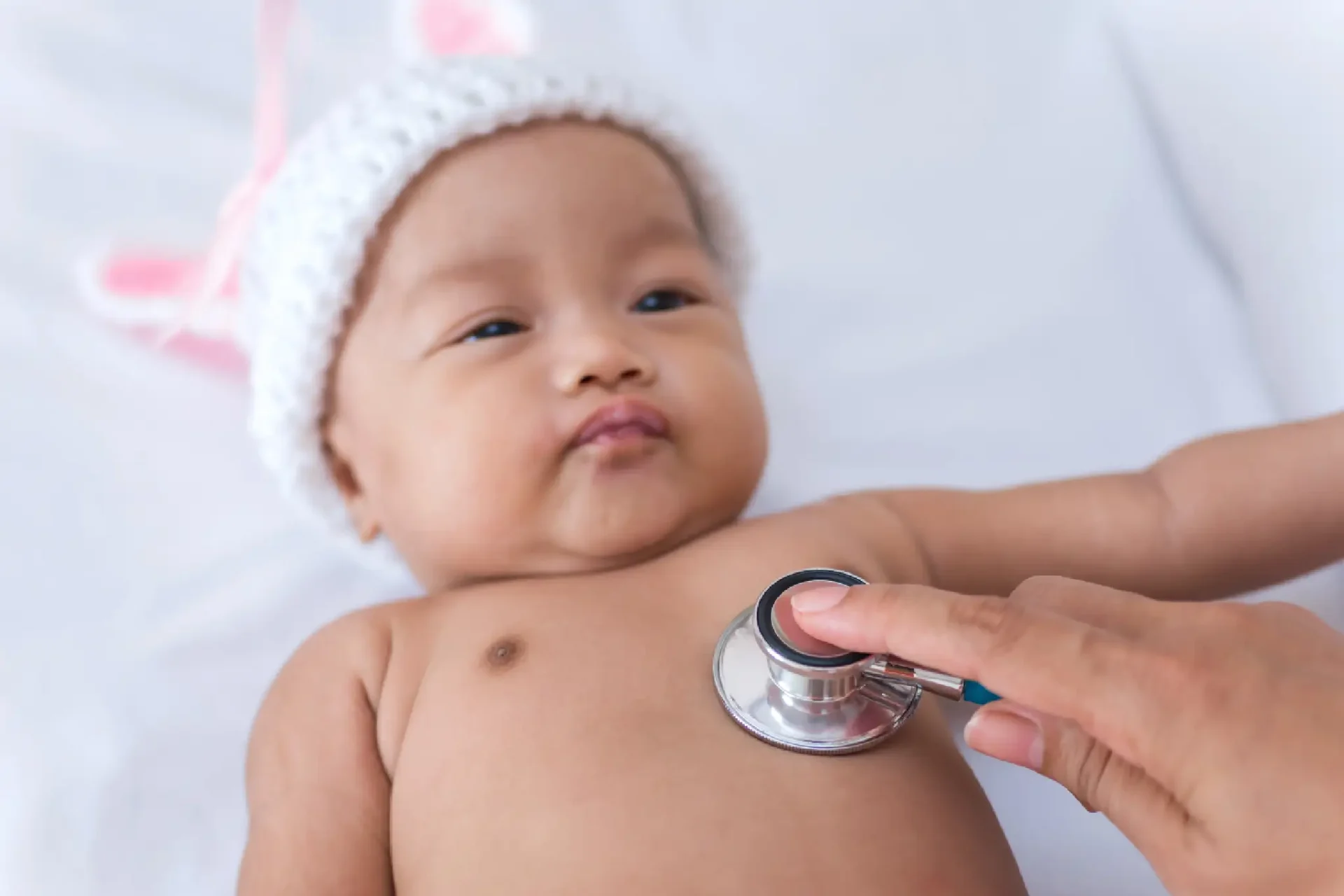 Baby in a bunny hat gets checkup.