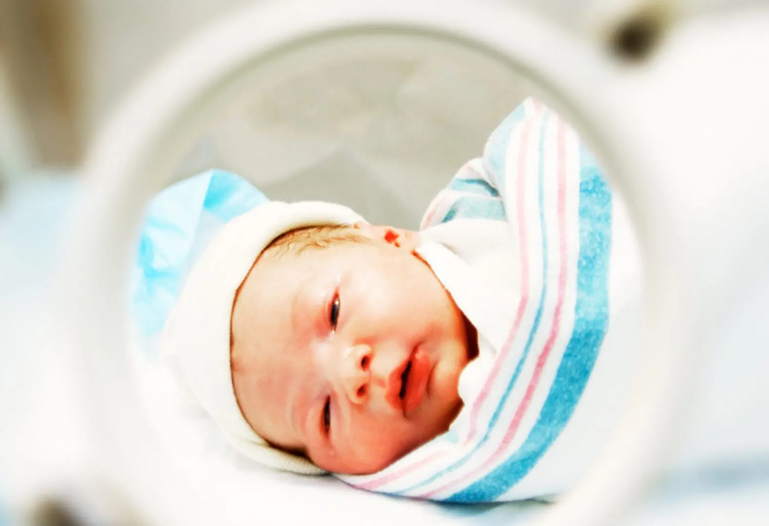 Newborn baby swaddled in blue and pink.