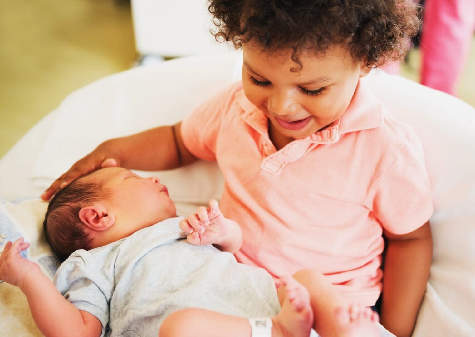 A child looks down at a newborn baby.