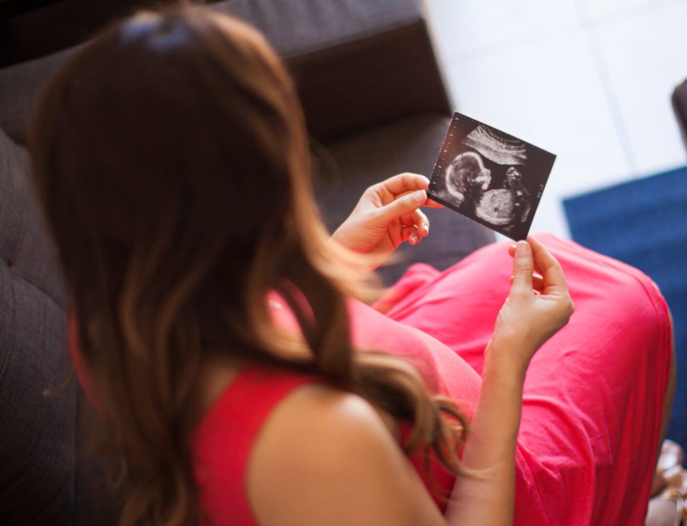 Pregnant woman holding an ultrasound photo.