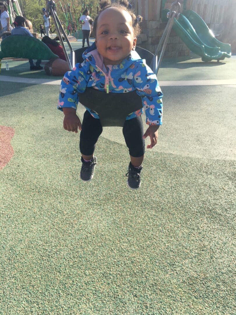 Happy baby swinging at playground.