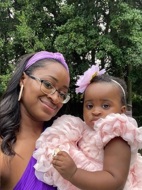 Smiling woman and baby in floral dresses.