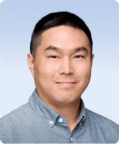 Man smiling in a blue button-up shirt.