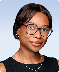 Person wearing glasses, smiling, against blue background.