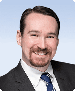 Smiling man in suit with blue tie.