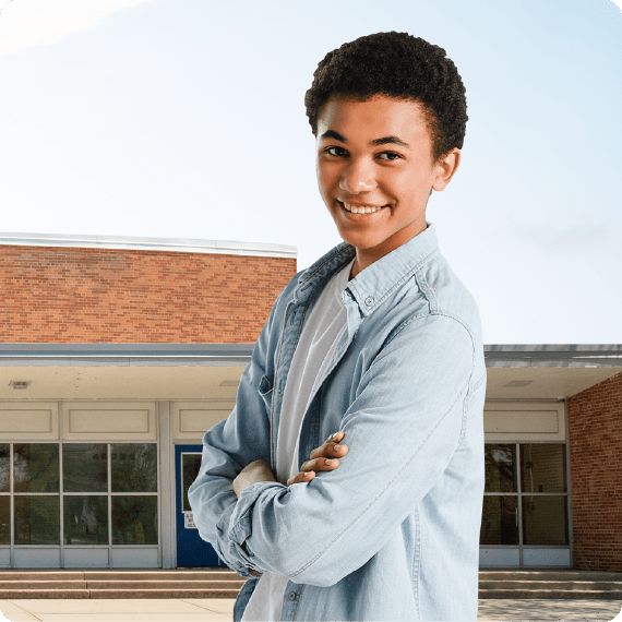 Smiling person in front of school building.