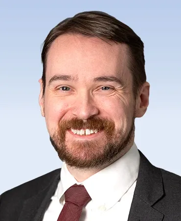 Smiling man in suit with beard.
