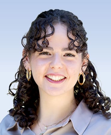 Smiling person with curly hair and earrings.