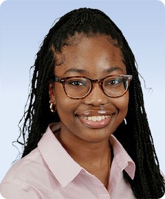 Smiling woman with glasses and braided hair.