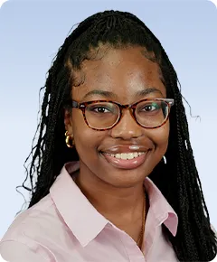 Smiling person wearing glasses and braids.