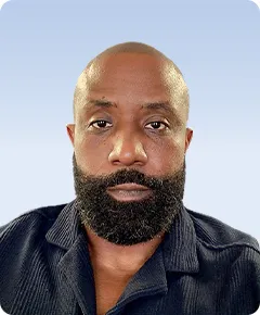 Man with beard, wearing dark blue shirt.
