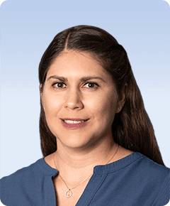 Woman smiling against a light blue background.