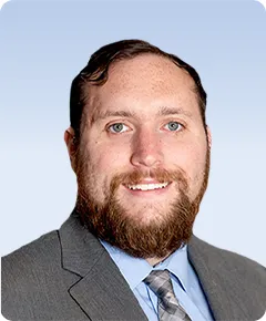 Man in suit with a beard smiling.