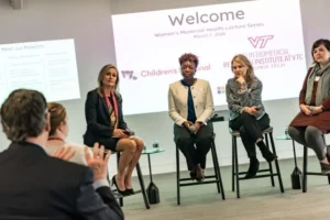 Four panelists seated beneath a welcome slide