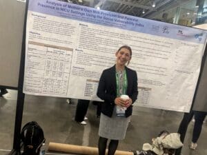 Conference attendee posing before NICU poster display