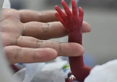 Newborn baby's hand held by adult.