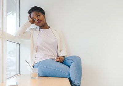 Woman sitting by window, looking away.