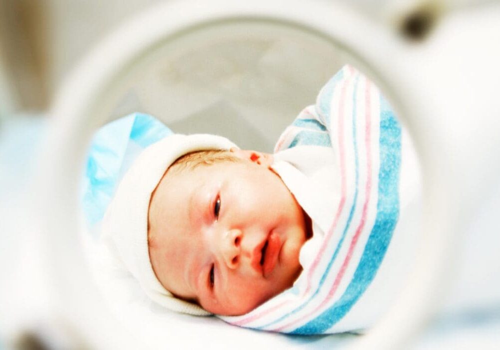 Newborn baby swaddled in blue and pink.