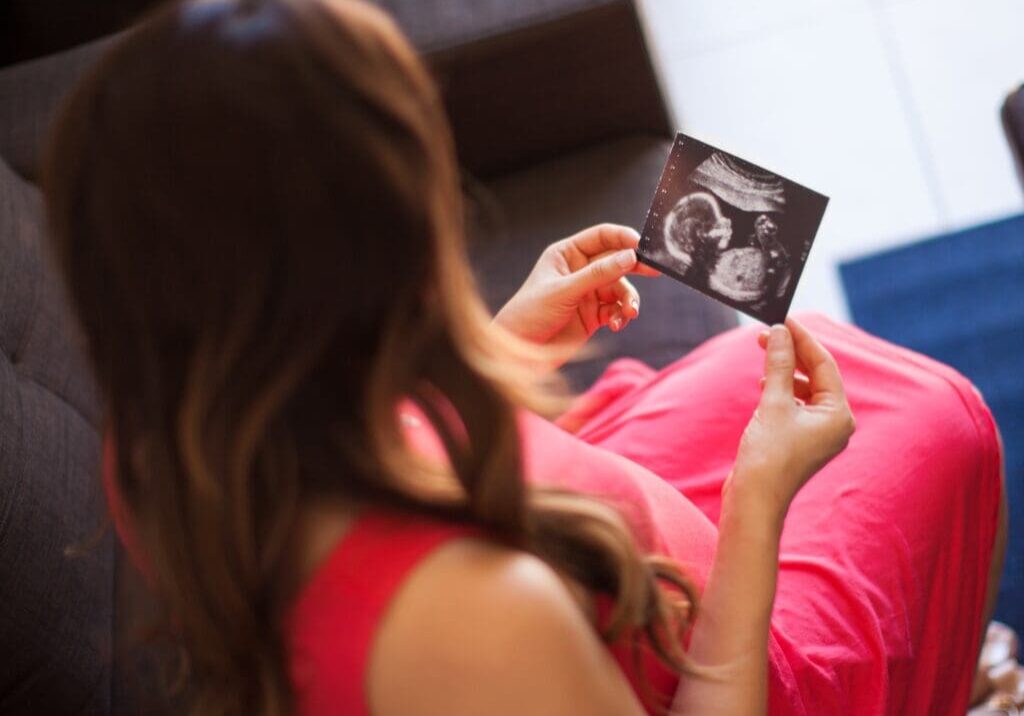 Pregnant woman holding an ultrasound photo.