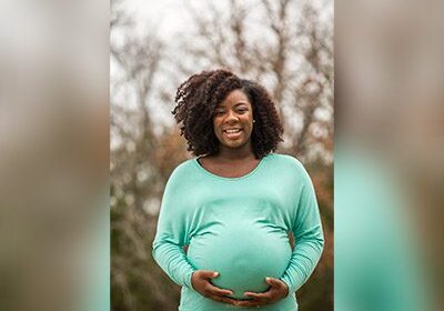 Smiling pregnant woman in a green shirt.