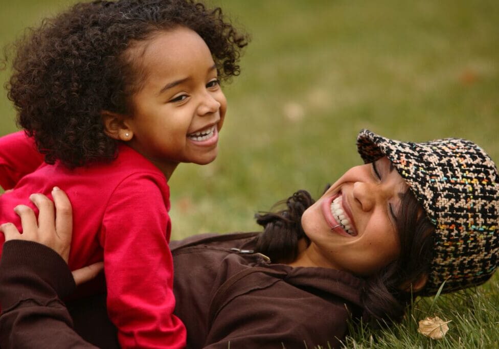 Laughing mother and daughter in grass.