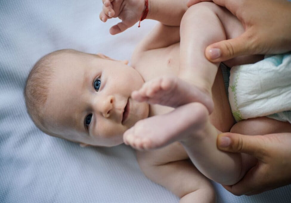 Baby with blue eyes lying on a white sheet.