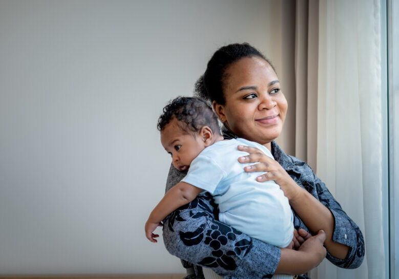 African family, 2-month-old baby newborn son is half-African halt-Thai on mother's shoulder,