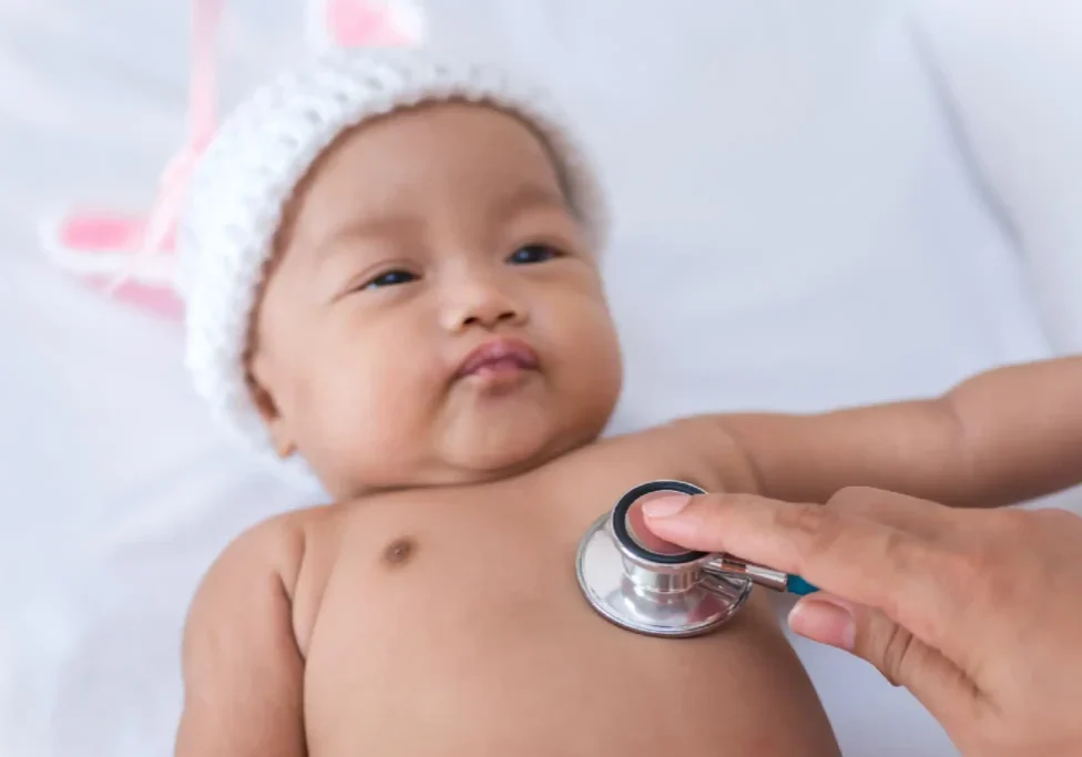 Baby in a bunny hat gets checkup.