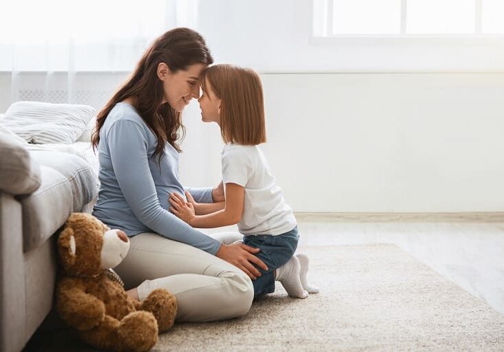 Pregnant woman and daughter cuddling.