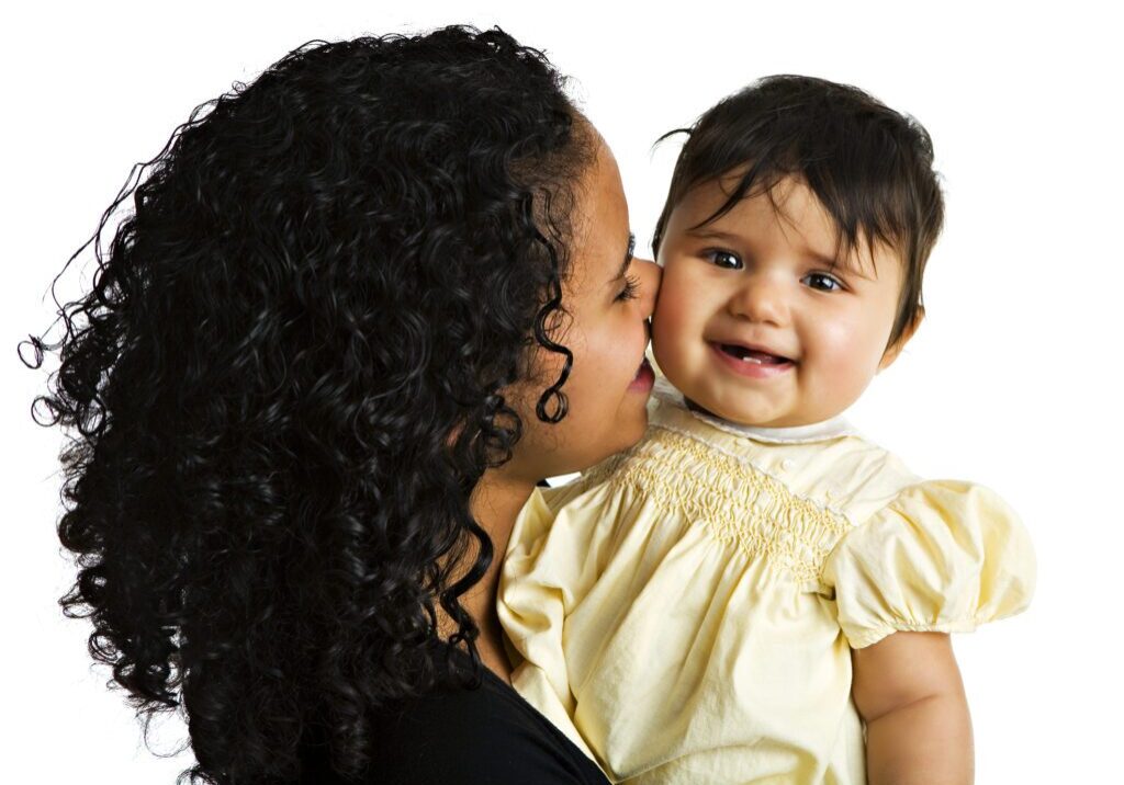 A Brazilian mom kissing her biracial baby. Isolated on white.